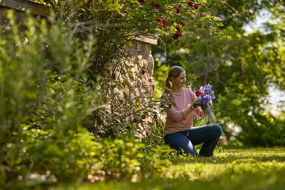 Rural1st_2026_01XX_Website_StoryBodyImage1_960x640_MacCanfieldAndKarinaBrandt_FINAL Woman tends to flowers on rural property financed by Rural 1st in Kansas