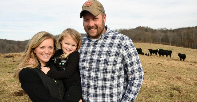 Family standing in cattle field.