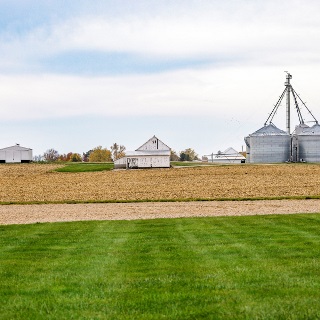 Farm landscape with white barn and metal grain bins, bought with an agricultural loan from Farm Credit Mid-America.