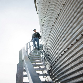 Man walks down a grain bin staircase.