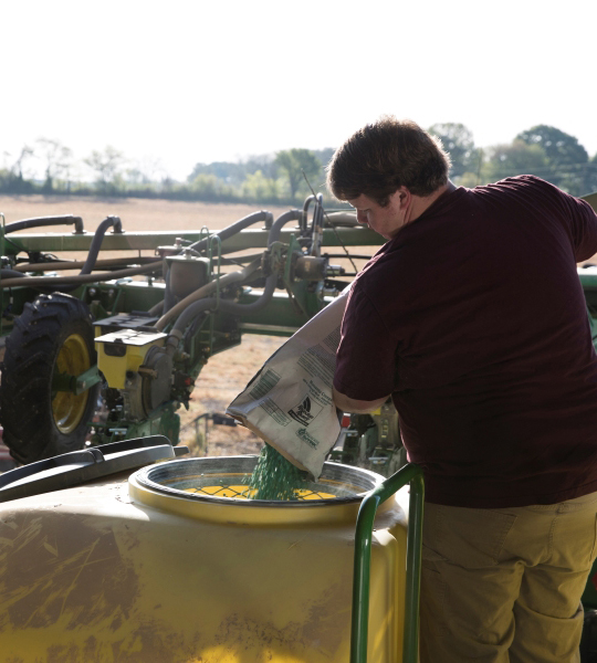 Farmer pours seed into planter.