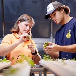 Teacher and high school student in greenhouse.