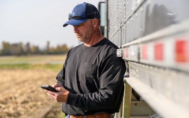 Man checks his phone next to grain semi.