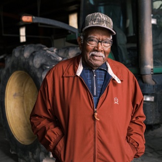 Man in standing in front of green tractor.