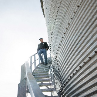 Man walks down grain bin stairs.