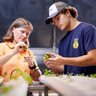 A teacher and student look at plants.